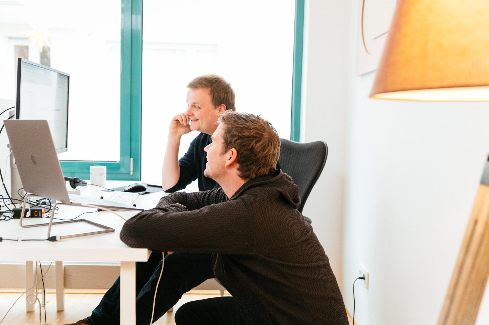 Christian und Axel im Büro: Zusammen vor einem Bildschirm.